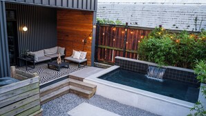 Une terrasse extérieure moderne, dotée d’un jacuzzi, d’une plateforme en bois et d’un espace salon.