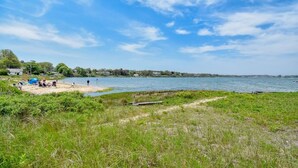 A lakeside beach with people relaxing and a clear sky.