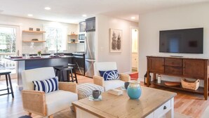A modern kitchen with a dining area, a living room with a TV, and a cozy seating arrangement.