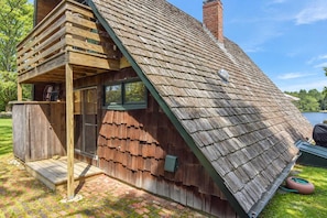 Une cabane en bois avec un toit en pente, une véranda et une petite terrasse.