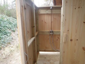 Eine Holzsauna mit schlichtem Design, einer Duschbrause aus Metall und einer hölzernen Sitzbank.
