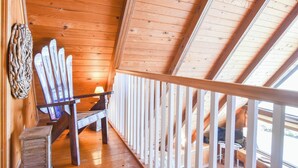 Un intérieur en bois avec un plafond en pente, une chaise en bois et une rambarde.