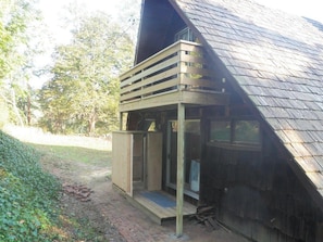 A wooden cabin with a sloped roof, a porch with a bench, and a small door. - Dream Waterfront A-Frame in Orleans! (Orleans)