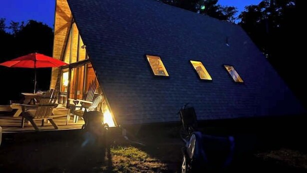 Un bâtiment triangulaire doté d’une terrasse et d’un espace extérieur aménagé pour s’asseoir.
