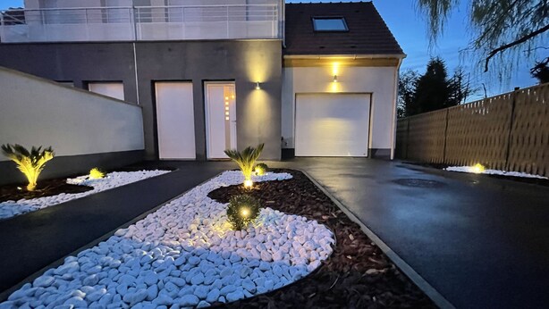A modern house with a driveway, a landscaped garden with white pebbles, and a garage. - Paris House (Villejust)