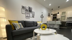 A modern living room with a grey sofa, a round coffee table, and a kitchen area in the background. - Paris House (Villejust)