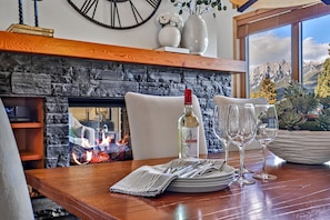 Une table à manger avec une cheminée, une bouteille de vin blanc et des verres à vin.
