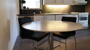 Une cuisine moderne avec des armoires blanches, un four encastré et une table de salle à manger ronde, assortie de chaises noires.