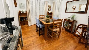 Un coin repas avec une table et des chaises en bois, une machine à café et une bibliothèque.
