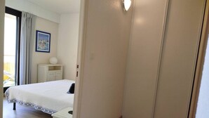 Un dormitorio con cama, mesita de noche, lámpara y ventana con cortinas.