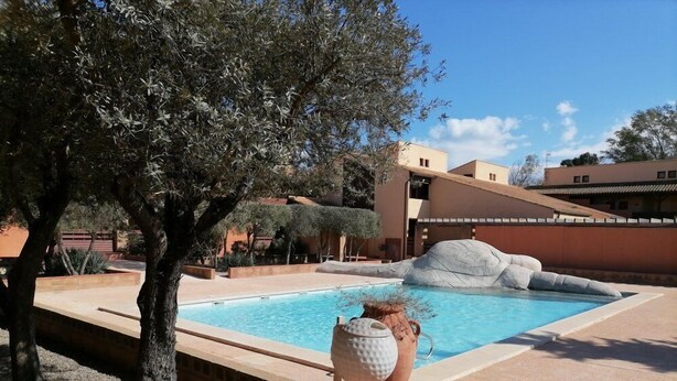 Una piscina con un muro de piedra y un árbol en primer plano.
