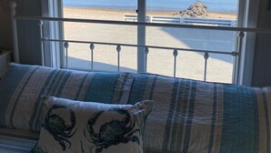 A room with a bed facing a window overlooking a beach. - Waterfront Beach House (Clinton)