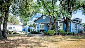 A two-story house with a blue exterior, surrounded by trees and a grassy yard. - Mega House: 7 bed 3 bath! King & Queen beds! (Irving)