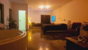 Una habitación de hotel moderna con una bañera grande, un sofá, un televisor y un escritorio.