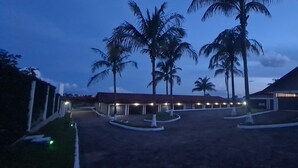 Un hotel con un espacio exterior cubierto, palmeras y un edificio de techo inclinado.
