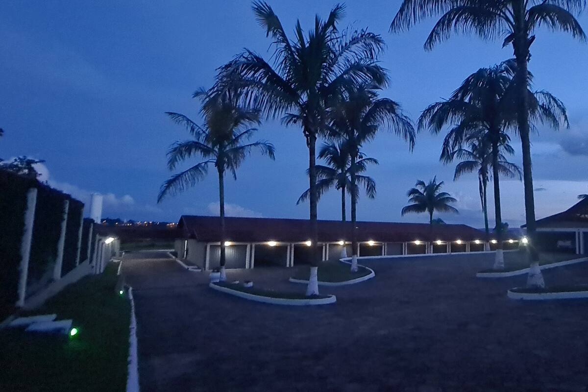 A hotel with a covered outdoor area, palm trees, and a building with a sloped roof.