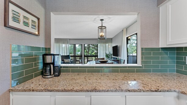 A kitchen with a coffee maker, a dining area with a table and chairs, and a view of the outdoors. - Pinseeker, a greenside condo on No. 5 - Walk to Pinehurst Clubhouse (Pinehurst)