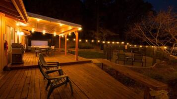 An outdoor deck with wooden flooring, a covered seating area, and string lights.