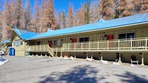 Un motel con techo azul, un porche cubierto y un estacionamiento nevado.