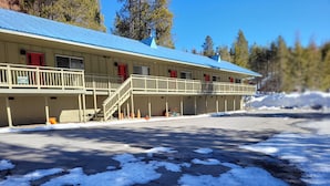 Un motel con techo azul, zona de estacionamiento techada y suelo cubierto de nieve.