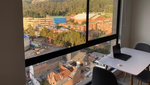 Una stanza con una grande finestra che offre vista su un paesaggio urbano con edifici e una montagna.