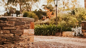 A stone wall with a number plaque, a lamp post, and surrounding greenery. - Mintaro Cottage (Mintaro)