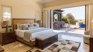 Ein Schlafzimmer mit einem großen Bett, einem Nachttisch, einer Bank und Blick auf eine Außenpatio mit Pool und Sitzgelegenheiten.