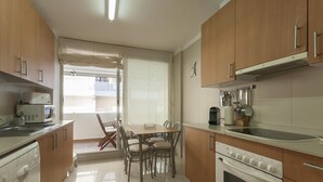 A modern kitchen with wooden cabinets, a dining table with chairs, a microwave, a coffee maker, and an oven. - EXCELLENT APARTMENT NEXT BEACH 7 (Tossa de Mar)