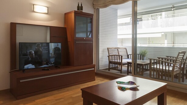 A living room with a TV, wooden cabinet, and a table with a decorative item. - EXCELLENT APARTMENT NEXT BEACH 7 (Tossa de Mar)