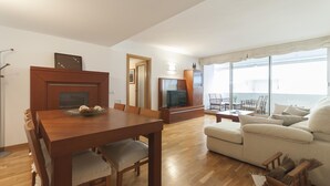 A living room with a wooden dining table, a sofa, and a TV. - EXCELLENT APARTMENT NEXT BEACH 7 (Tossa de Mar)