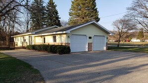 Une maison de plain-pied avec un garage à l’avant, une véranda et une allée menant au garage.
