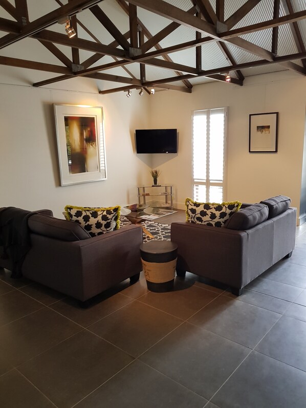 Un salon avec deux canapés, un téléviseur et une petite table sur laquelle est posée une plante.