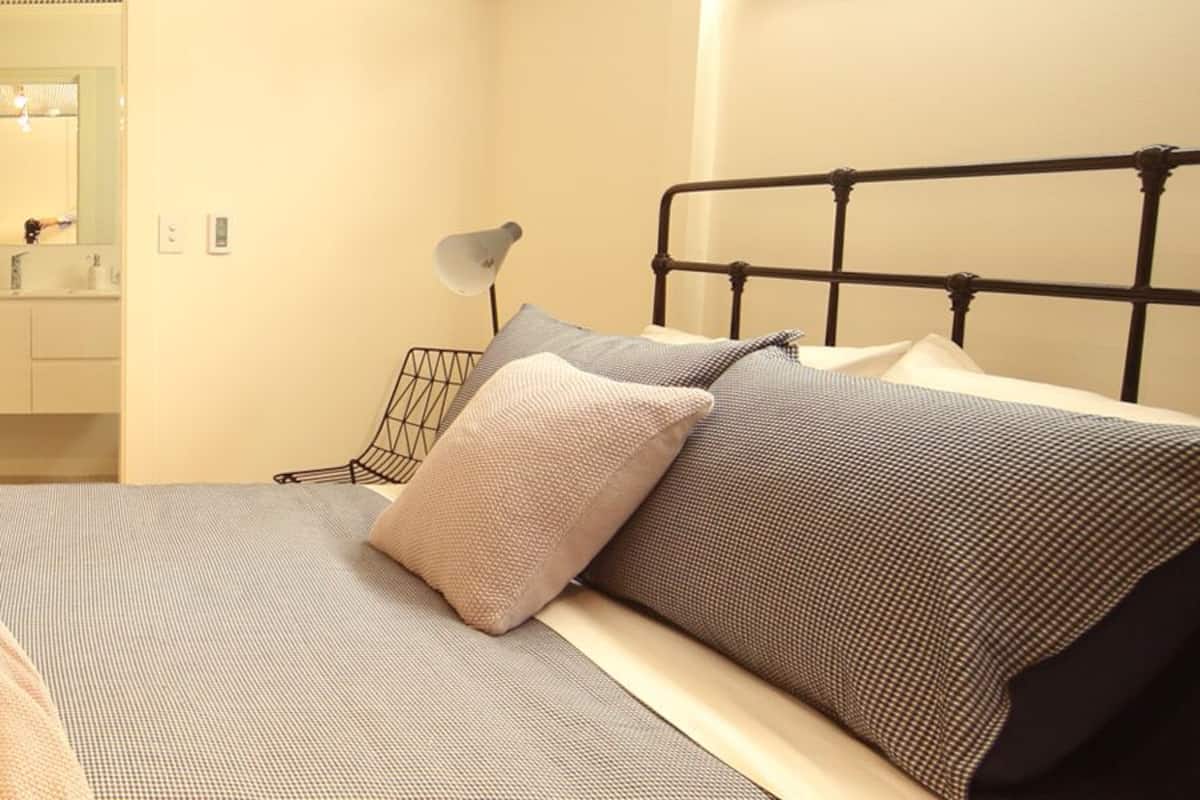 A bedroom with a bed, a bedside table, a lamp, and a mirror.