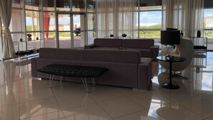 A spacious living area with large windows, a sofa, a coffee table, and a lamp. - Studio Business West Flat (Mossoró)