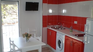 A compact kitchen with red and white tiles, a washing machine, and a dining area with a table and chairs. - Apartment in Conil de la Frontera, Cádiz (Conil de la Frontera)