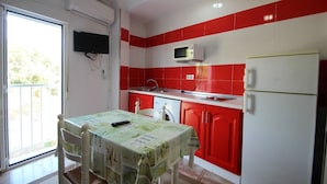 A compact kitchen with red and white tiles, a microwave, a refrigerator, a washing machine, and a dining table with chairs. - Apartment in Conil de la Frontera, Cádiz (Conil de la Frontera)