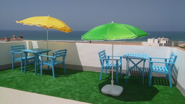 A terrace with blue chairs and tables, two umbrellas, and a view of the sea. - Apartment in Conil de la Frontera, Cádiz (Conil de la Frontera)