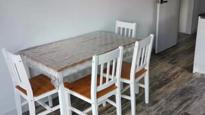 Ein Essbereich mit einem rechteckigen Tisch und vier weißen Stühlen mit Holzsitzen.