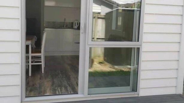 Eine Glastür führt zu einer überdachten Terrasse mit Holzdeck.