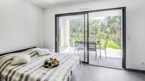 A bedroom with a bed, a tray of breakfast items, and a sliding glass door leading to an outdoor patio with a table and chairs. - Domaine d'Arca by Interhome (Porto Vecchio)