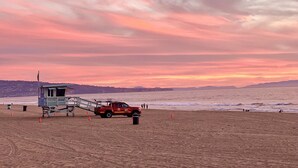 A lifeguard tower with a red vehicle parked nearby on a beach. - NEW! Ocean View Beach House Steps from the Sand  (Manhattan Beach)