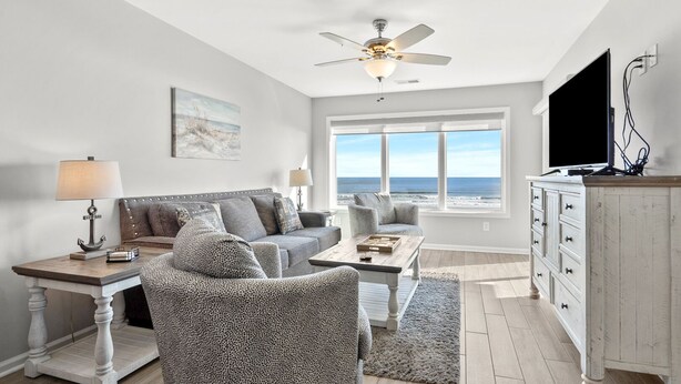 A living room with a sofa, armchair, coffee table, and TV stand.