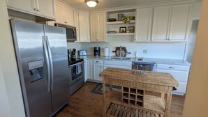 A modern kitchen with white cabinets, stainless steel appliances, and a wooden island. - Garden Creek Retreat - Remodeled Home with Luxury Furnishings (Challis)