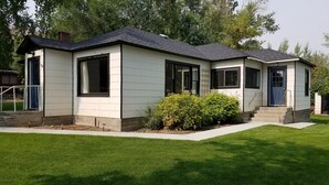 A single-story house with a dark roof, white siding, and a front porch. - Garden Creek Retreat - Remodeled Home with Luxury Furnishings (Challis)