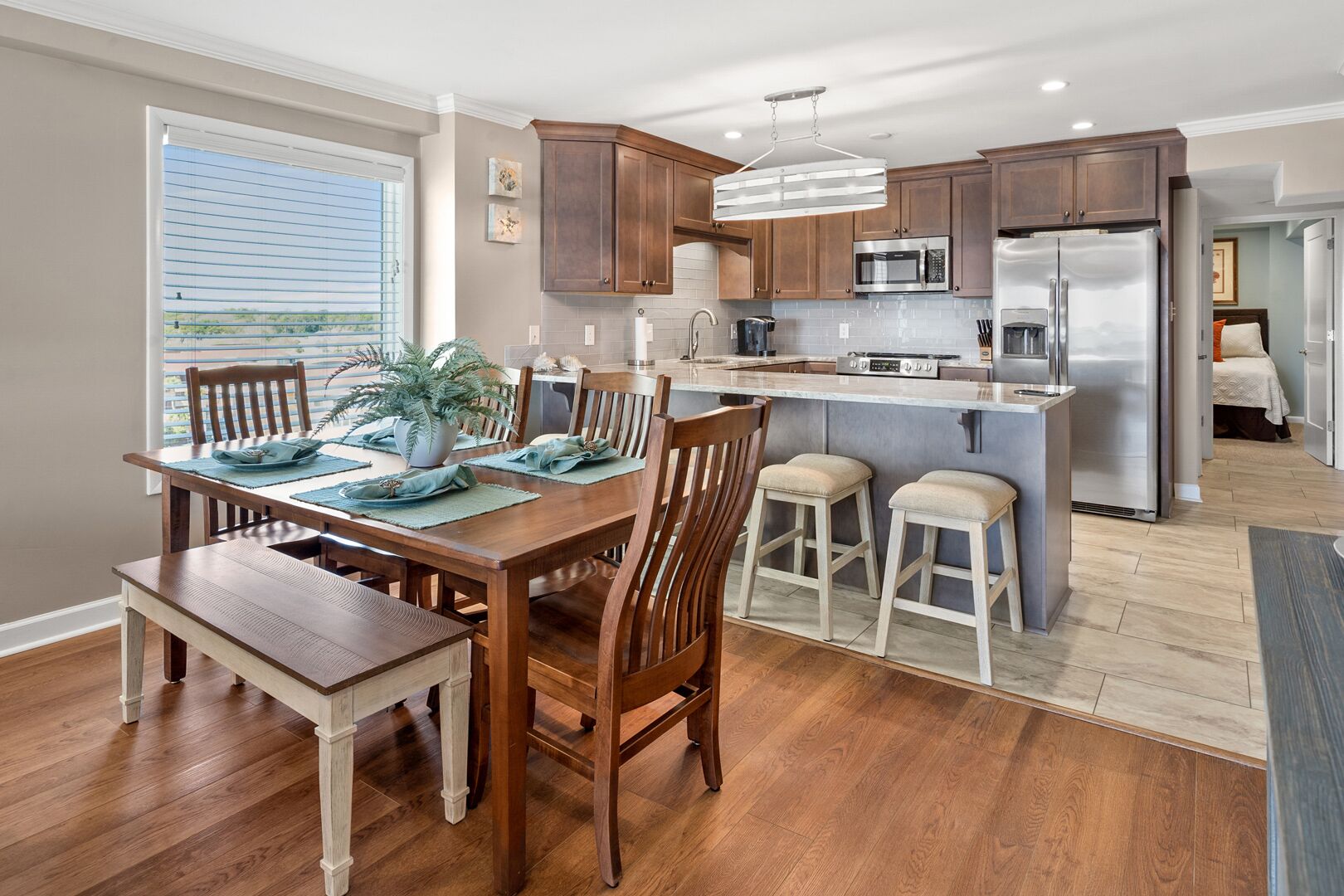 A modern kitchen with wooden cabinets, stainless steel appliances, and a central island with bar stools. - Upgraded oceanfront condo with pool, kid's pool and private balcony for plenty of sunrises & sunsets (North Myrtle Beach)