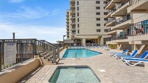 A pool area with two pools, lounge chairs, and a sign with pool rules. - Upgraded oceanfront condo with pool, kid's pool and private balcony for plenty of sunrises & sunsets (North Myrtle Beach)