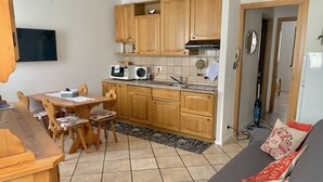 A compact living space with a kitchen area, dining table, and a sofa. - Il Mulino Pdl (Ponte di Legno)