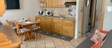 A compact living space with a kitchen area, dining table, and a sofa.