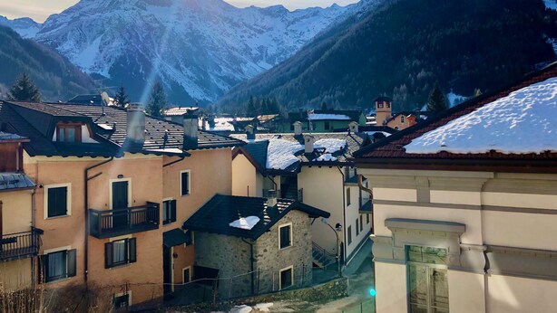 A mountainous village with traditional buildings, some with snow on the roofs, and a clear sky. - Il Mulino Pdl (Ponte di Legno)