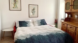 A bedroom with a bed, a small table, and a cabinet. - Il Mulino Pdl (Ponte di Legno)